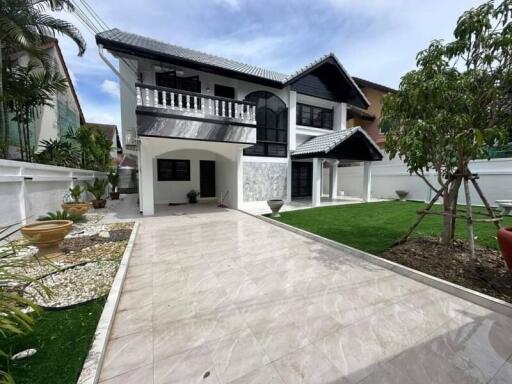 Front yard view of a residential building with garden and tiled pathway