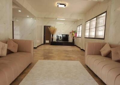 Spacious modern living room with two beige sofas, a white coffee table, and a TV on a stand