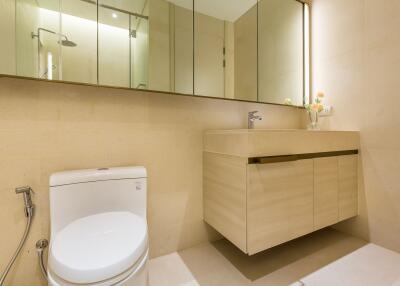 Modern bathroom with beige walls, a toilet, a floating sink cabinet, and a large mirror