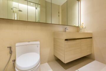 Modern bathroom with beige walls, a toilet, a floating sink cabinet, and a large mirror