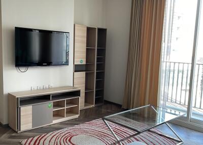 Modern living room with TV, shelving unit, glass coffee table, and large window