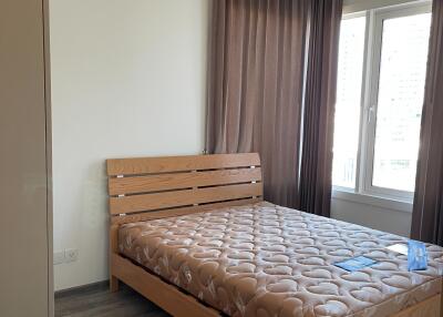 A bedroom with a wooden bed frame, mattress and large windows.