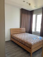 A bedroom with a wooden bed frame, mattress and large windows.