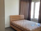 A bedroom with a wooden bed frame, mattress and large windows.