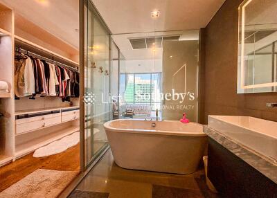 Modern bathroom with glass shower, bathtub, and walk-in closet