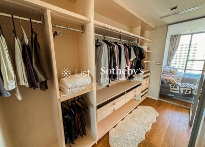 Spacious walk-in closet with hanging clothes and drawers, connected to bedroom with natural light