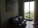 Living room with black leather sofa and large window