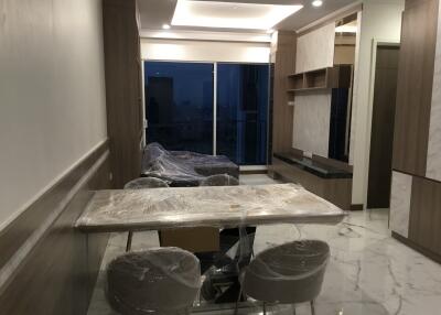 Modern living area with dining table and chairs covered in protective plastic