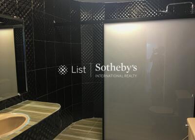 Modern bathroom with dark tiles and frosted glass shower door