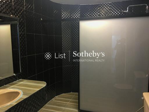 Modern bathroom with dark tiles and frosted glass shower door