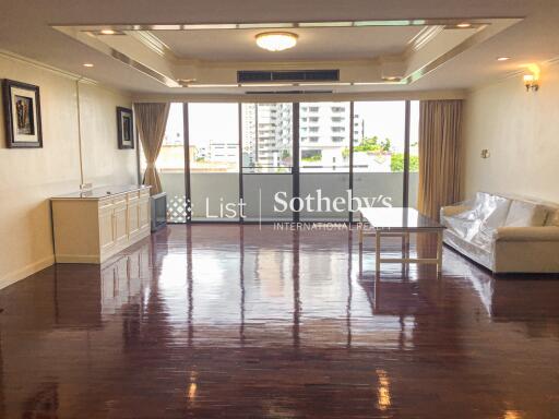 Spacious living room with large windows and polished wooden floors