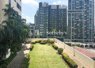 A well-maintained communal garden with modern high-rise buildings in the background