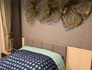 Photo of a bedroom with a modern design, featuring a bed with patterned bedding, wall art above the headboard, and a bedside table with a lamp