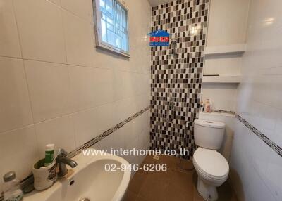 Bathroom with sink, mirror, toilet, and shower with tiled wall