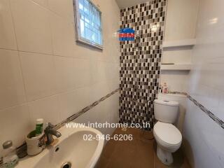 Bathroom with sink, mirror, toilet, and shower with tiled wall