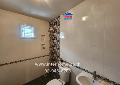 Modern bathroom with tiled walls, sink, and toilet