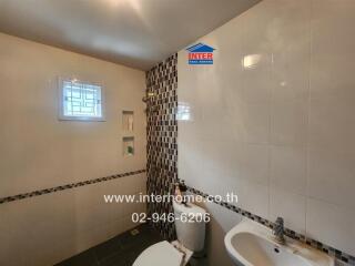 Modern bathroom with tiled walls, sink, and toilet