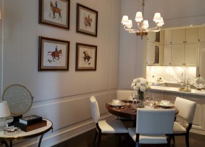 Elegant dining area with round table, chairs, and kitchen in the background