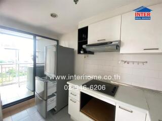 Modern kitchen with white cabinets, stainless steel appliances, and a balcony view.