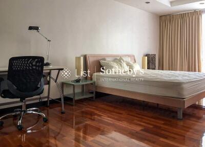 Spacious bedroom with wooden flooring, a desk, and natural lighting from a large window