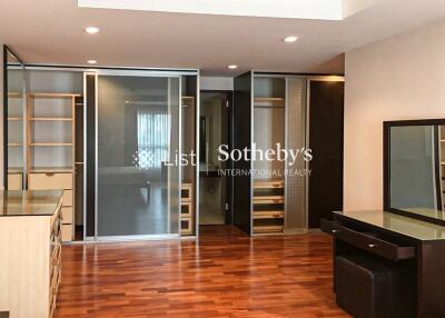 Spacious bedroom with wooden floor, built-in wardrobes, and dressing table