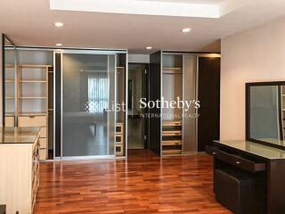 Spacious bedroom with wooden floor, built-in wardrobes, and dressing table