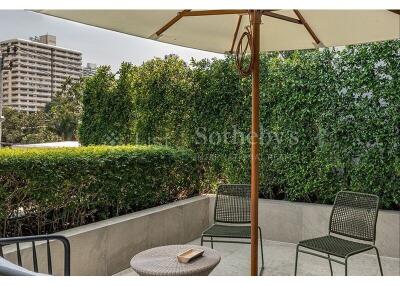 Outdoor patio with chairs and table, surrounded by greenery