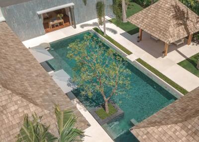 Aerial view of a luxurious outdoor pool area with a manicured garden and shaded seating