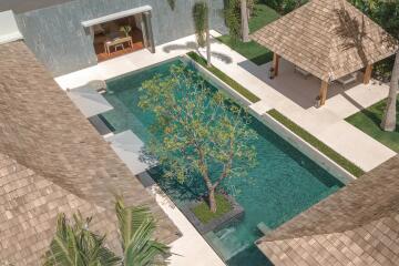 Aerial view of a luxurious outdoor pool area with a manicured garden and shaded seating