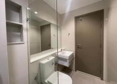 Modern bathroom with large mirror, sink, and toilet