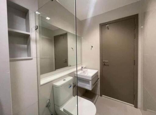 Modern bathroom with large mirror, sink, and toilet