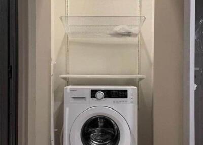 Compact laundry area with a Hitachi washing machine and shelving