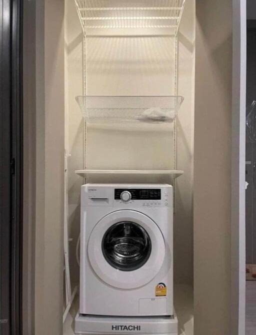 Compact laundry area with a Hitachi washing machine and shelving