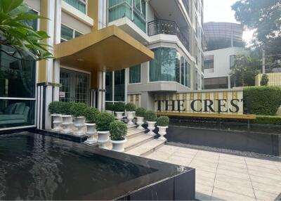 Exterior view of a modern building with landscaping, water features, and a sign reading 