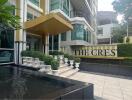 Exterior view of a modern building with landscaping, water features, and a sign reading 'The Crest'