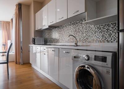 Modern kitchen with appliances, mosaic backsplash, and wooden flooring