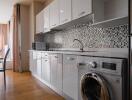 Modern kitchen with appliances, mosaic backsplash, and wooden flooring