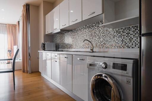 Modern kitchen with appliances, mosaic backsplash, and wooden flooring