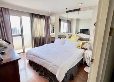 Bright bedroom with a large bed, sliding glass doors to a balcony, and floor-to-ceiling mirrors.