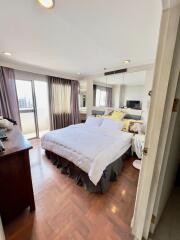 Bright bedroom with a large bed, sliding glass doors to a balcony, and floor-to-ceiling mirrors.