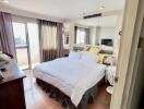 Bright bedroom with a large bed, sliding glass doors to a balcony, and floor-to-ceiling mirrors.