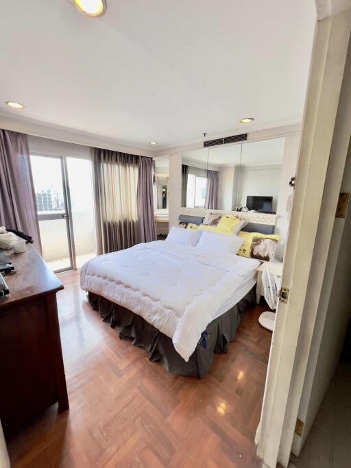 Bright bedroom with a large bed, sliding glass doors to a balcony, and floor-to-ceiling mirrors.