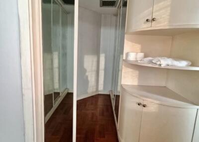 Bedroom with wooden floors, mirrored closet doors, and built-in shelving unit