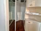 Bedroom with wooden floors, mirrored closet doors, and built-in shelving unit