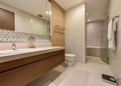 Modern bathroom with a large mirror, vanity, toilet, and glass-enclosed shower