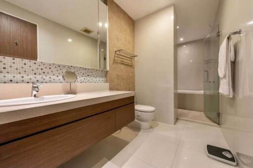 Modern bathroom with a large mirror, vanity, toilet, and glass-enclosed shower