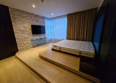 Modern bedroom with platform bed, large windows, and a wall-mounted TV