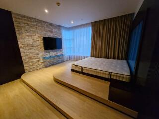 Modern bedroom with platform bed, large windows, and a wall-mounted TV