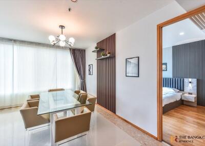 Modern dining area with glass table and six chairs, view into a modern bedroom