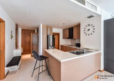 Modern kitchen area with sleek countertops, bar seating, and a clock on the wall